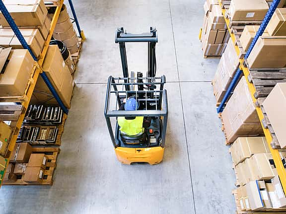 Aerial view of a forklift in a large warehouse, showcasing grenke's financing options for electric and diesel-powered forklifts to enhance efficiency and safety in warehouse and distribution operations.